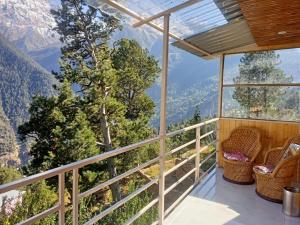 a balcony with chairs and a view of the mountains at The Shudarang Inn in Kalpa