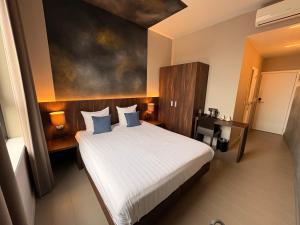 a bedroom with a large white bed with blue pillows at Hotel Elisabeth in Mechelen