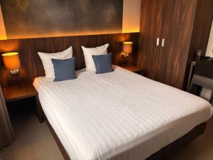 a bedroom with a large bed with two blue pillows at Hotel Elisabeth in Mechelen