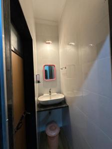 a bathroom with a sink and a mirror and a toilet at Sai Homestay Tarkarli in Malvan