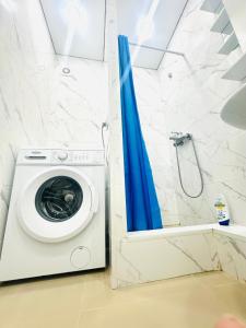 a washing machine in a bathroom with a blue shower curtain at City in Uralsk