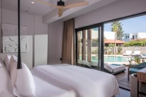 a bedroom with a large white bed and a pool at Noble Hotel & Suites - Adults Only in Gouves
