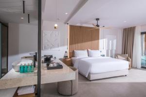a bedroom with a white bed and a desk with a table at Noble Hotel & Suites - Adults Only in Gouves