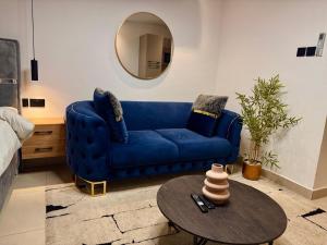 a blue couch in a living room with a table at Tranquil Studio in Belrose Place, Accra in Accra