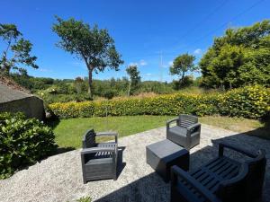 a patio with three chairs and a table at Charmante maison de campagne in Commana