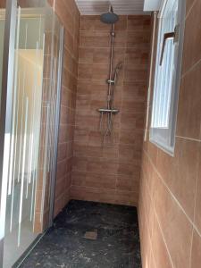 a shower in a bathroom with brown tiles at Charmante maison de campagne in Commana
