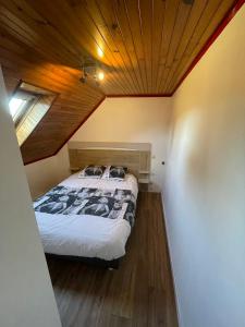 a bed in a room with a wooden ceiling at Charmante maison de campagne in Commana