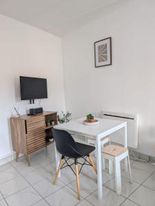 a white table and chair in a room with a tv at les studios du canal in Eckbolsheim