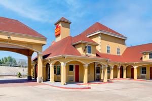 a hotel with a red roof and a building at Capital O Deluxe Inn Channelview Houston I-10 in Channelview