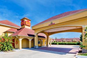 a large yellow building with a red roof at Capital O Deluxe Inn Channelview Houston I-10 in Channelview