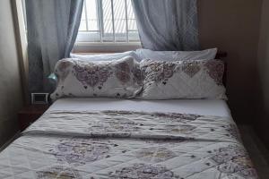a bed with white sheets and pillows next to a window at 1 Bed Apartment Sleeps 4 with Free Parking in Kasoa