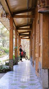 a woman standing next to a motorcycle under a building at Homstay Páo Ấm Mai in Tát Lá