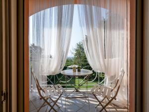 アスティにあるHoliday Home Villa Felice by Interhomeの白いカーテン付きのバルコニー(テーブル、椅子付)