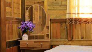 a bedroom with a mirror and a vase with purple flowers at Homstay Páo Ấm Mai in Tát Lá