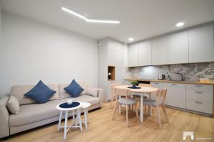 a living room with a couch and a table and chairs at Apartament Szmaragd&Perła by LookAp - parking gratis! in Poznań
