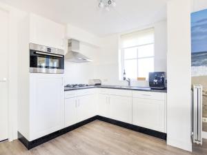 a white kitchen with white cabinets and a window at Holiday Home Tapuit 6-2 by Interhome in Noordwijk