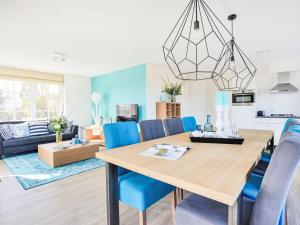 a dining room and living room with a wooden table and blue chairs at Holiday Home Tapuit 6-2 by Interhome in Noordwijk +10 photos