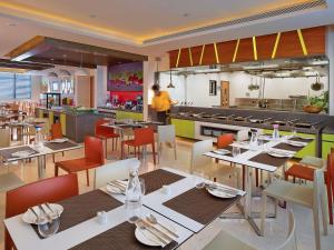 a restaurant with tables and chairs and a kitchen at ibis Chennai Sipcot - An Accor Brand in Chennai