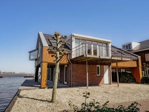 a house on the water with a tree at Apartment Penthouse by Interhome in Uitgeest
