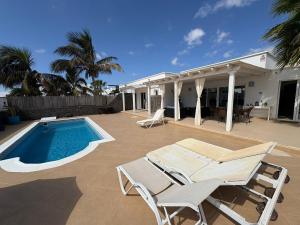 a patio with a pool and chairs and a house at Villa Queen Papagayo Vetusta in Playa Blanca