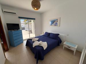 a bedroom with a blue bed and a television at Villa Queen Papagayo Vetusta in Playa Blanca +75 photos