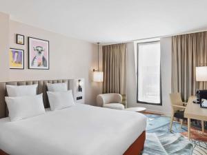 ein Hotelzimmer mit einem großen weißen Bett und einem Schreibtisch in der Unterkunft Mercure Amiens Cathédrale in Amiens + 100 Fotos