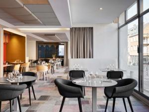a restaurant with tables and chairs and windows at Mercure Amiens Cathédrale in Amiens