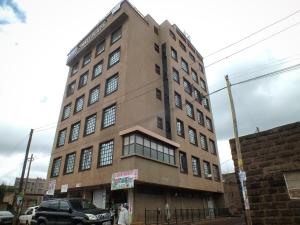 a tall brown building on a city street at Legatus Cozy Homes Ngong in Ngong