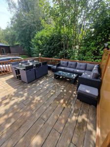 a patio with a couch and a table on a deck at Hot Tub Lake District Lodge - Windermere in Troutbeck Bridge