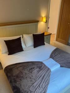 a large white bed with two pillows on it at Hot Tub Lake District Lodge - Windermere in Troutbeck Bridge +32 photos