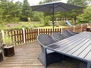 a table and chairs with an umbrella on a deck at Holiday Home Orpah - 2-5km from the sea by Interhome in Kongsmark