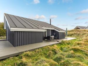 una casa con un tetto nero e una terrazza di legno di Holiday Home Casandra - 600m from the sea by Interhome a Fanø