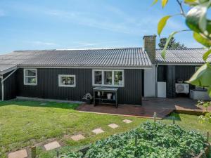 ein schwarzes Haus mit einer Terrasse in einem Hof in der Unterkunft Holiday Home Bisera - 150m from the sea by Interhome in Fåborg