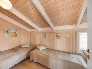 two beds in a room with wooden walls at Holiday Home Asol - 650m from the sea by Interhome in Løkken