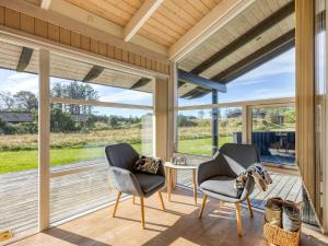 two chairs and a table in a room with a large window at Holiday Home Asol - 650m from the sea by Interhome in Løkken