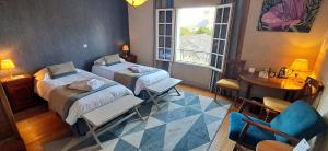 a hotel room with two beds and a table and a window at Logis Hôtel Le Bussy in Montsoreau