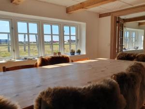 a large wooden table in a room with windows at Holiday Home Answald - 250m from the sea by Interhome in Harboør