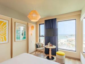 a bedroom with a bed and a table and a window at Mercure Président Biarritz Plage in Biarritz +84 photos
