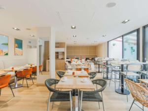 a dining room with tables and chairs and windows at Mercure Président Biarritz Plage in Biarritz