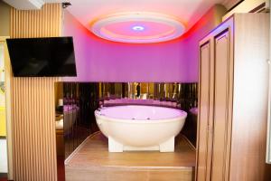 a bath tub in a bathroom with a purple wall at Hotel Deluxe in Tirana