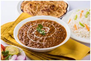 Un tazón de chile y un plato de arroz y un naan en Hotel Subh Aura Suites - Near Kashi Vishwanath Temple And Ganga Ghat -With Fully Air conditioned- Wifi - Room Service - A Luxury Room in Varanasi, en Varanasi
