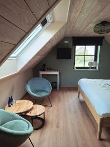 a bedroom with a bed and two chairs and tables at B&B Heinehoeve in Kaprijke