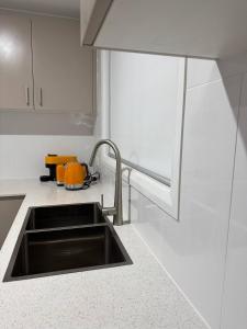 a kitchen with a sink in a white kitchen at Bran new home with ducted AC to stay in Sydney in Oakhurst
