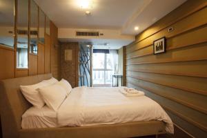 Un dormitorio con una cama blanca con una pared de madera. en Harmony Living Condominium, en Makkasan