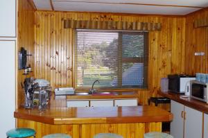 eine Küche mit Holzwänden und einer Theke mit einem Fenster in der Unterkunft Tertia's Logcabin in Port Alfred