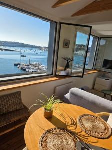a living room with a table and a view of a harbor at Anatoline - Appart'hotel vue mer - Sea View Apartments - Audierne in Audierne