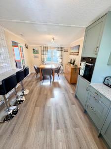 a kitchen and dining room with a table and chairs at Lovely spacious lodge on Trimingham house caravan park, near Cromer and Mundesley in Trimingham +9 photos