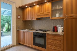 a kitchen with wooden cabinets and a stove top oven at Paradise house & garden in Lignano Sabbiadoro