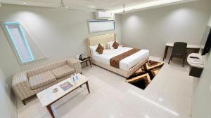 a bedroom with a bed and a couch and a table at Hotel Nova Vista in Rajkot