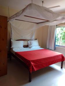 ワタムにあるSikuMoja Watamu 4 Bed HolidayHomeのベッドルーム1室(天蓋付きベッド1台、赤い毛布付)